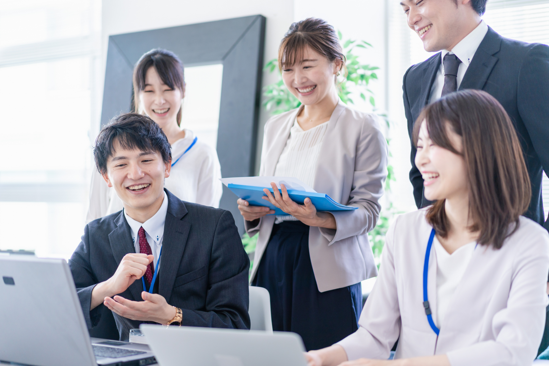 不動産会社の店舗でエンジニアと担当者がノートパソコンを一緒に確認しながら議論している様子