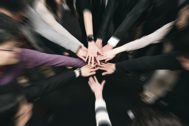 不動産会社のチームが手を重ね合い一丸となって取り組む様子